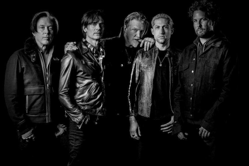 black and white photo of five members of Queens Of The Stone Age standing side by side