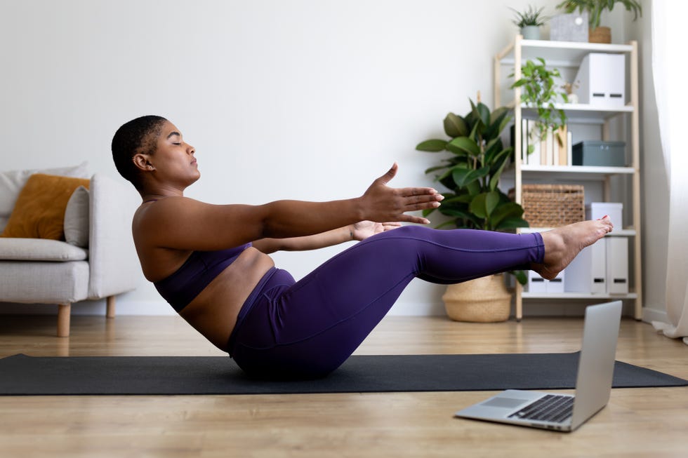 Young woman doing yoga exercises at home following online tutorial young woman practicing yoga at home following online tutorial on laptop