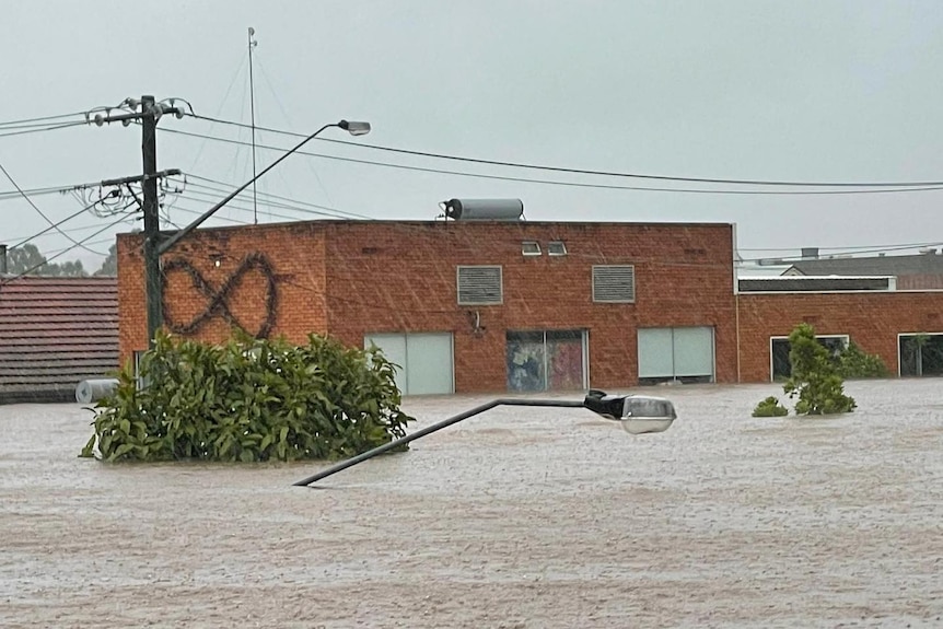 A brick building surrounded by flood water up to the second storey windows.