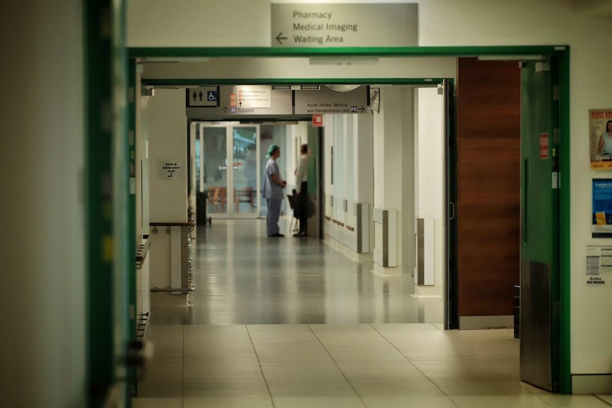 Medical staff chat in a long hospital corridor.