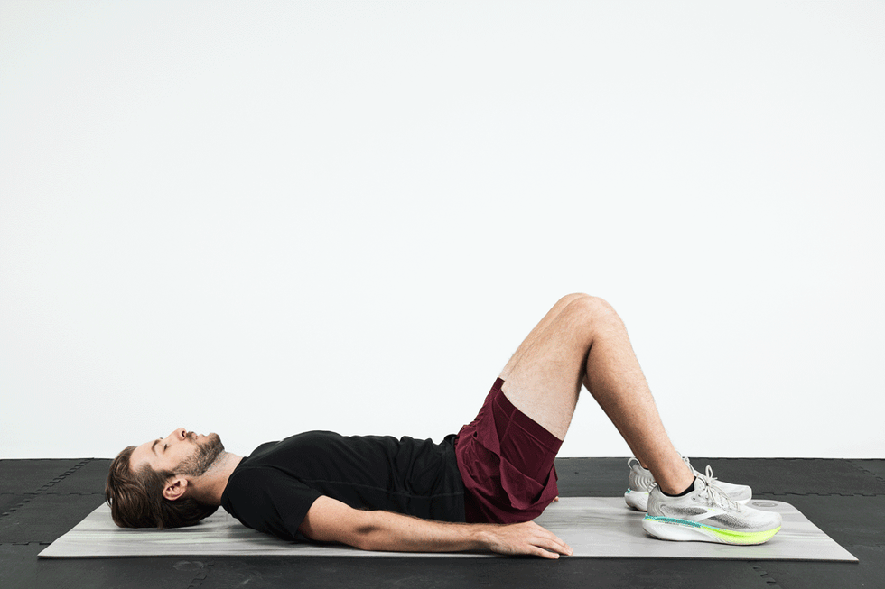 Man performing an exercise on a yoga mat with knees bent and feet flat on the ground. Man performing an exercise on a yoga mat with knees bent and feet flat on the ground.