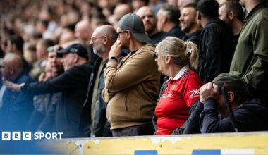 Manchester United fans look on during the Premier League 2026/27 match between Hull City and Manchester United at MKM Stadium. One fan in the foreground appears to have their head in their hands.