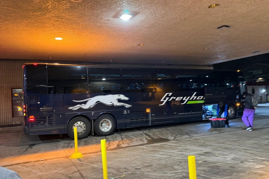 A Greyhound bus at a depot at night time.