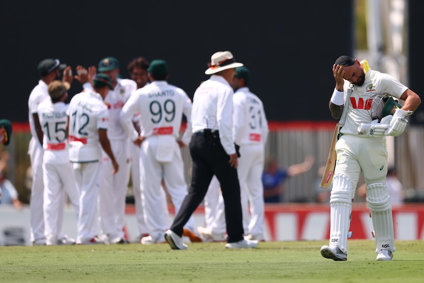 A cricket batter rubs his head and departs the field after being dismissed