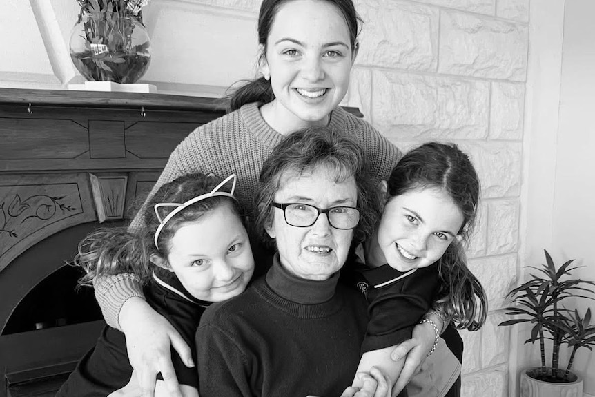 A grandmother surrounded by her three grandchildren.