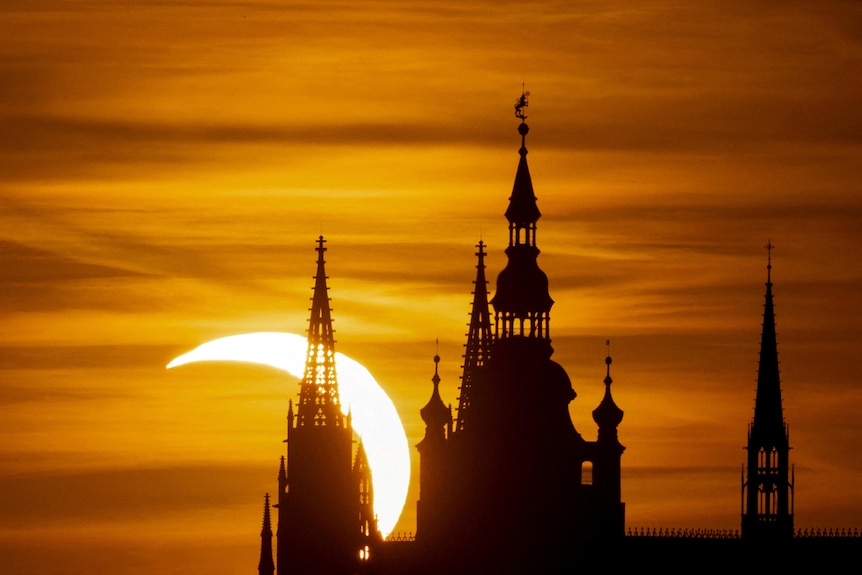 The prague castle silhouette in front of a partial solar eclipse.
