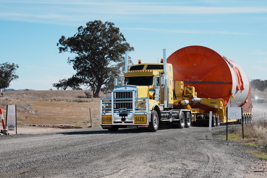 A truck carrying a large load driving on a dirt road.