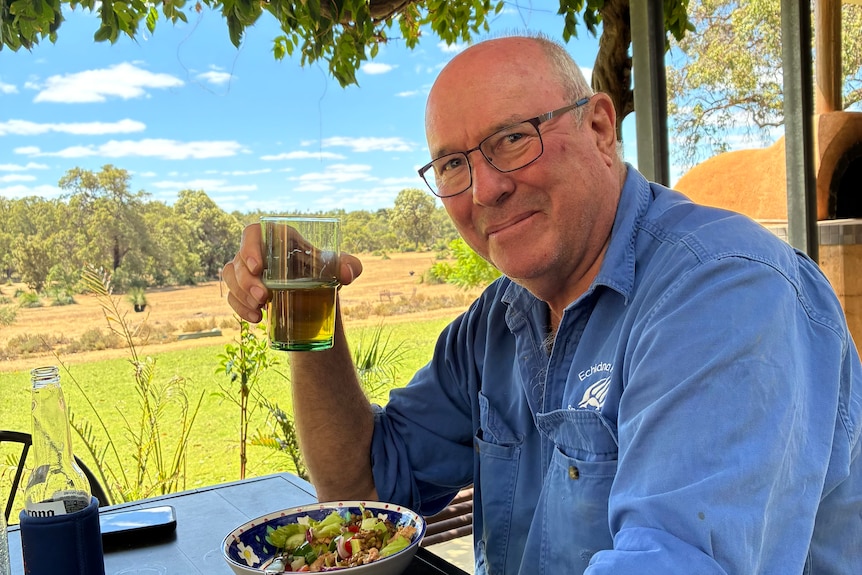 Ian Grant holds a glass of beer and smiles at the camera.