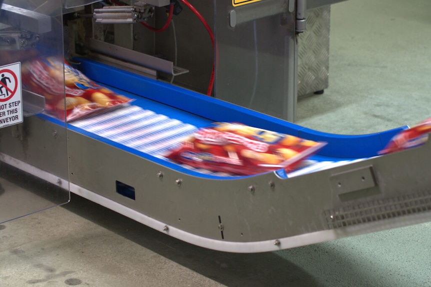 Red bags of potato products zip along on blue and silver conveyor belts.