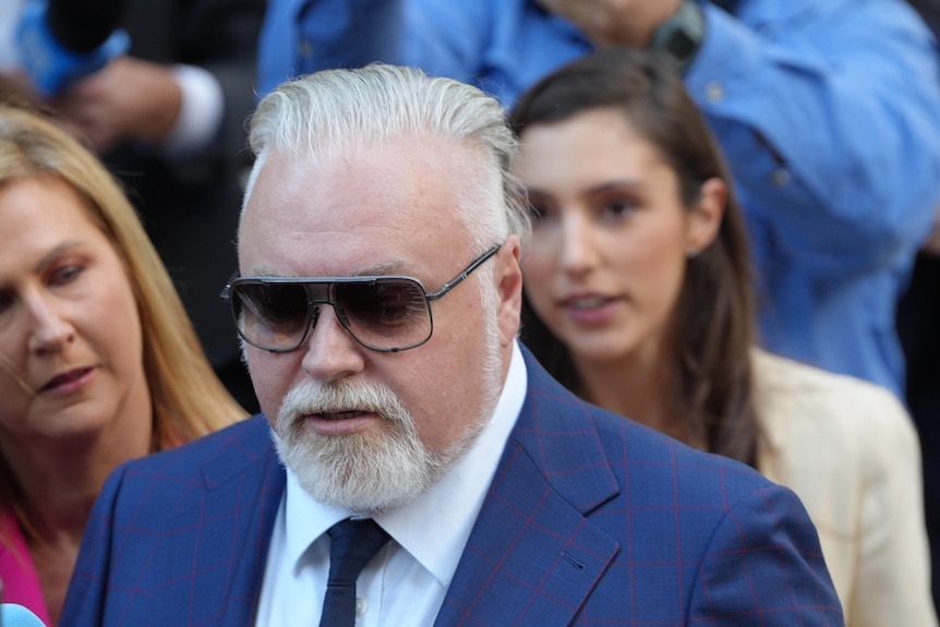 Sandilands wearing a navy suit and sunglasses
