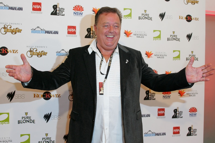 A man opens his arms while arriveing on the red carpet.