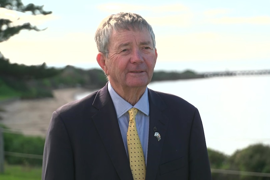 Mayor Michael Pengilly in a suit and tie with a beach in the background