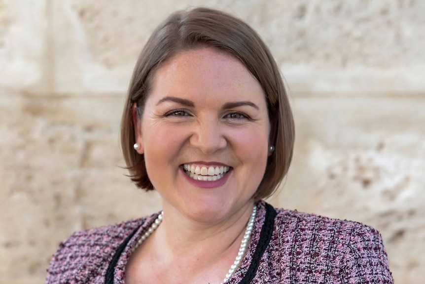A caucasian woman with short brown hair and brown eyes smiling