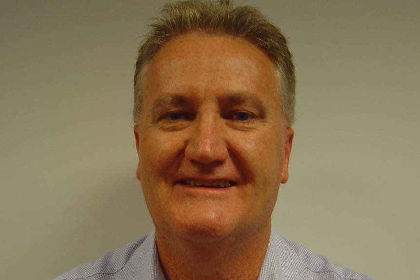 Ian, a man with brownish hair, grey around the edges, smiling, blue shirt with collar.