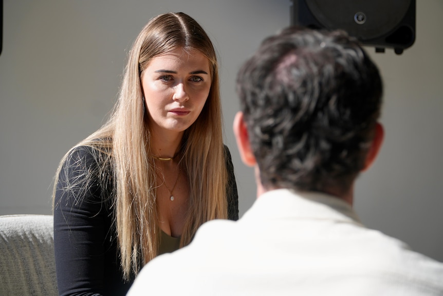 Tess McKenna sits opposite a man in an office.