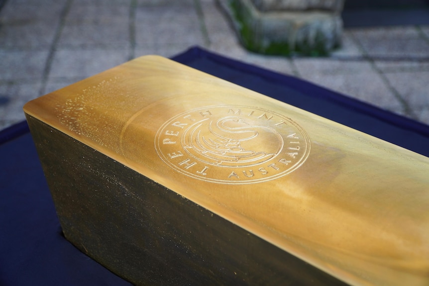 A huge gold bar on display on a table.