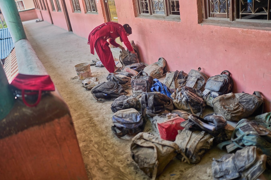 a woman rumages thorugh mud covered school bags