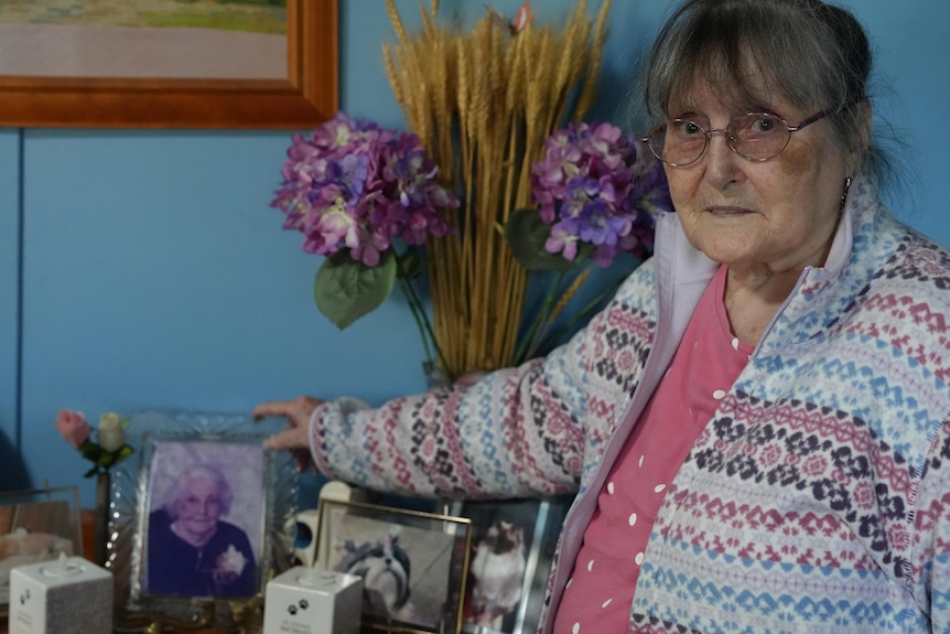A woman places a hand on a photo frame featuring another woman.