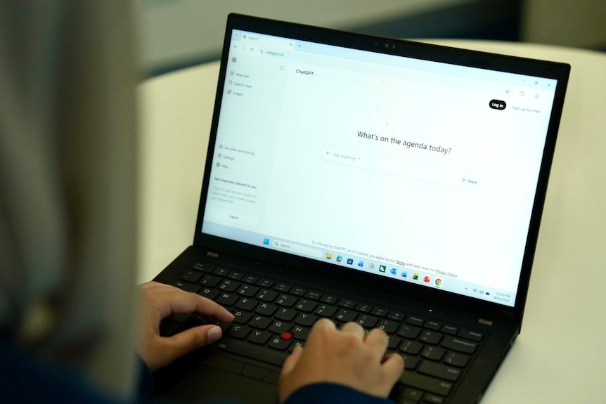 Hands typing on a laptop which displays a chatgpt website.