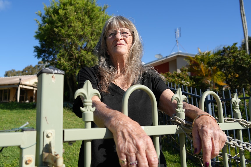 woman staring into distance from behind fence