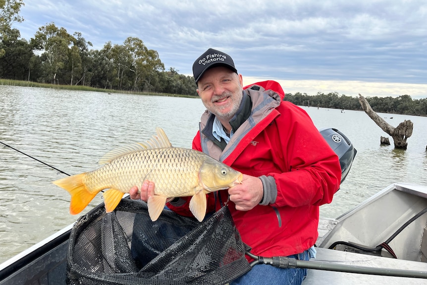 Man in red jacket with a 1-metre long European carp.
