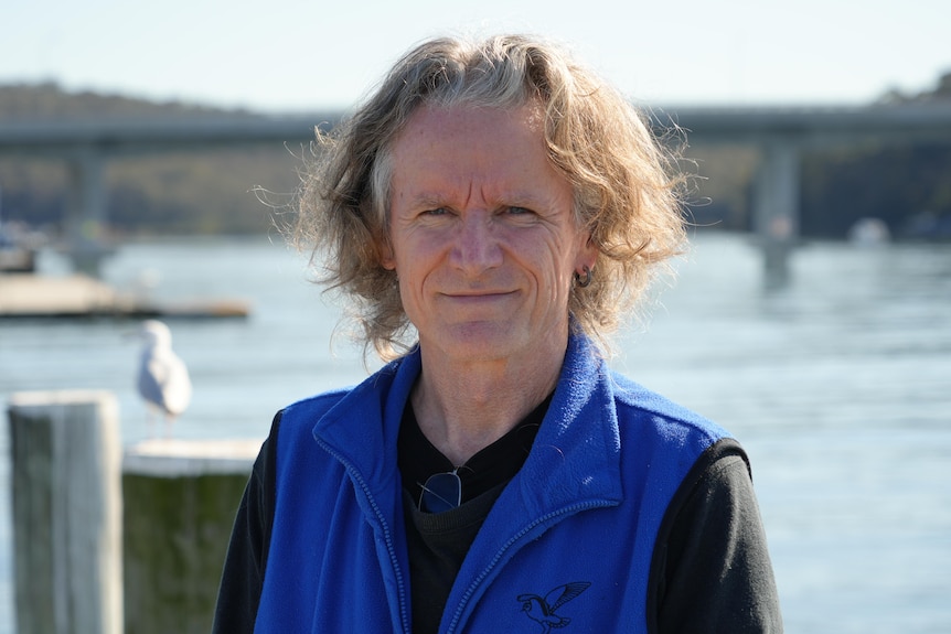 A man stands on a pier looking at the camera