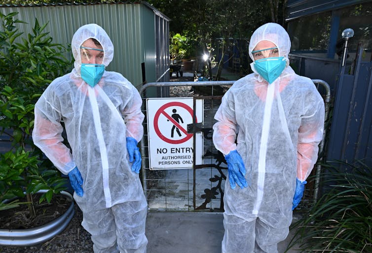 two women dressed in gauzy white biosecurity suits, bird flu.