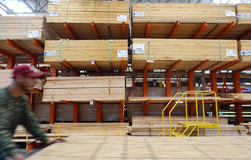 A customer pushes a cart through the lumber section of Home Depot. The company said it will use $730 million in tariff refunds to offset higher costs, such as energy.