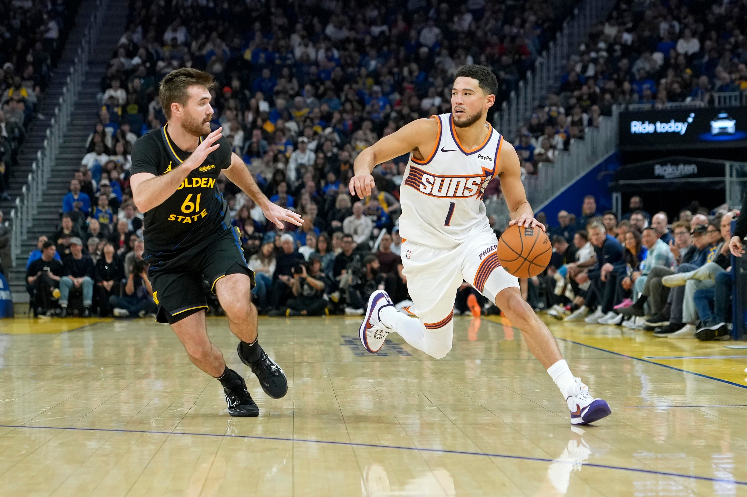 SAN FRANCISCO, CALIFORNIA - DECEMBER 20: Devin Booker #1 of the Phoenix Suns dribbles the ball up court past Pat Spencer #61 of the Golden State Warriors in the first half of an NBA basketball game at Chase Center on December 20, 2025 in San Francisco, California. NOTE TO USER: User expressly acknowledges and agrees that, by downloading and or using this photograph, User is consenting to the terms and conditions of the Getty Images License Agreement. (Photo by Thearon W. Henderson/Getty Images)