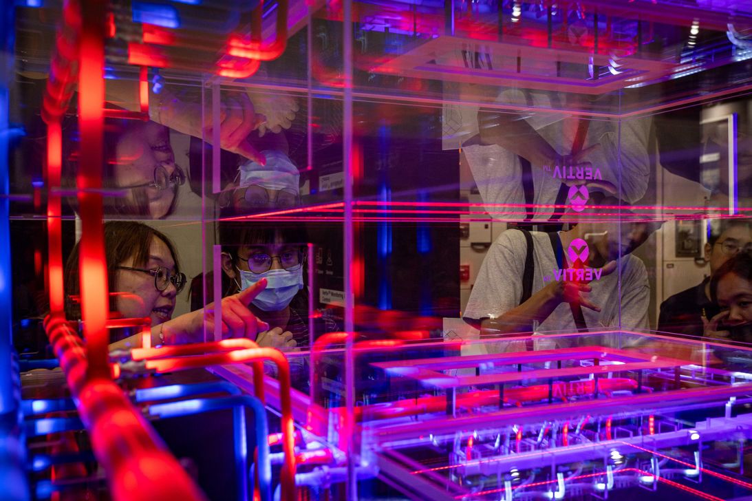 Visitors look at red and blue neon-lit cooling pipelines of a data center infrastructure model on June 03, 2026 in Taipei, Taiwan.