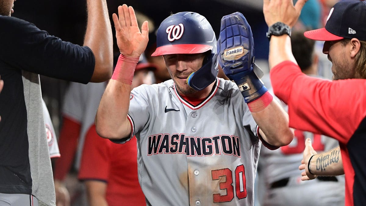 Jacob Young high-fives teammates in the dugout after scoring in the ninth inning.