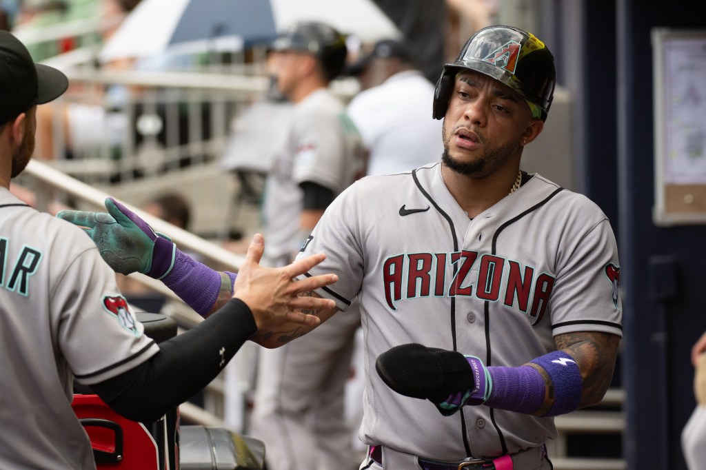 Ketel Marte in a dugout high-fiving a teammate after scoring a run.