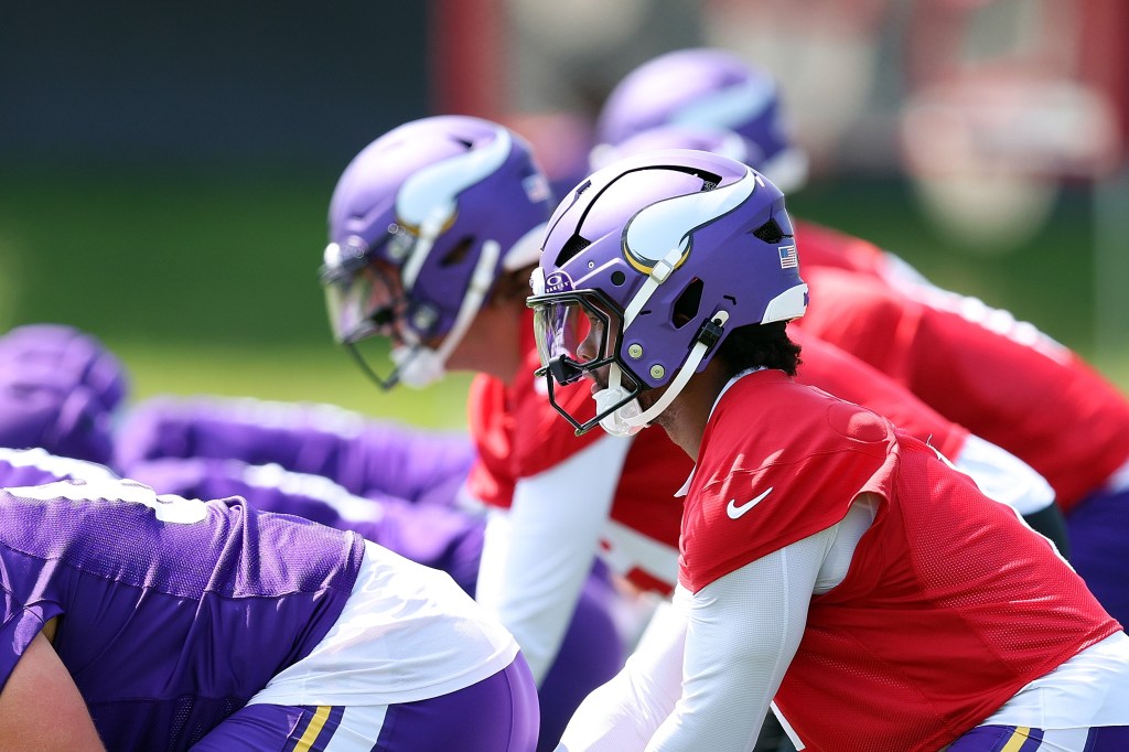 Kyler Murray of the Minnesota Vikings in red practice jersey and purple helmet participates in a drill during training camp.