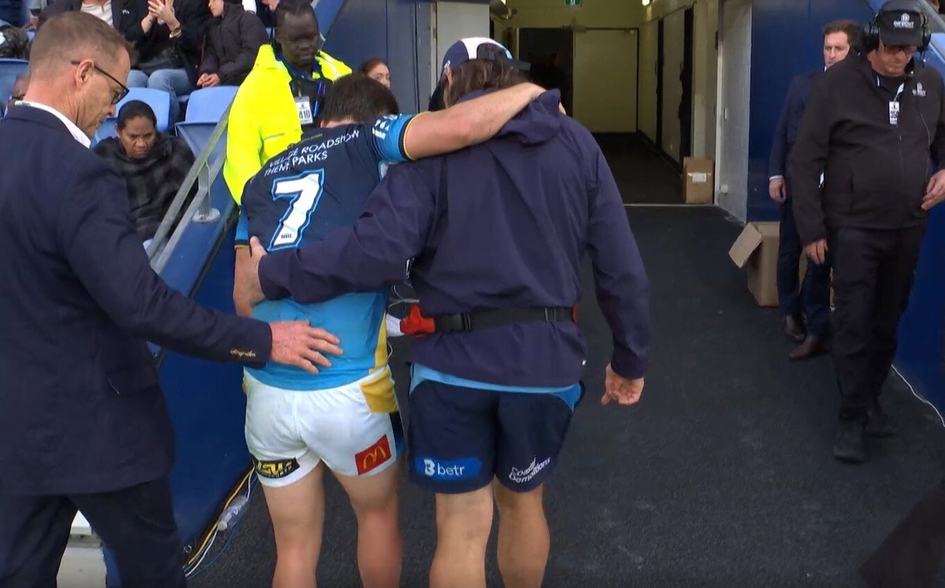 Gold Coast Titans player helped by trainer going up the tunnel, limping