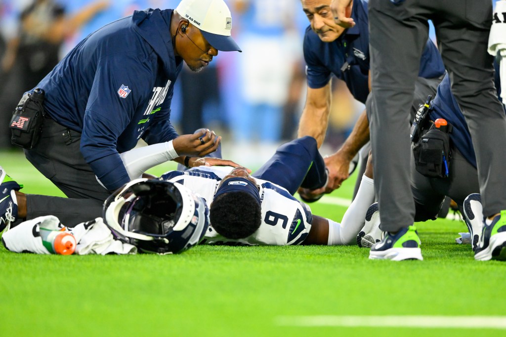 A Seattle Seahawks trainer holds the ankle of safety Bud Clark (9) as they wait for a cart during a game against the Tennessee Titans.