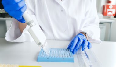 A gloved scientist in a lab uses a device to insert multiple samples into a tray with many openings.
