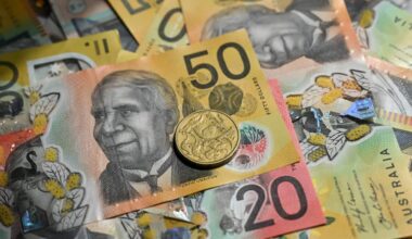 A selection of Australian bank notes and coins laid out in a pile.