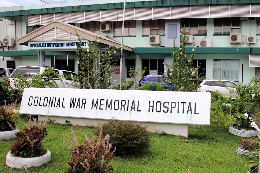 A hospital with a sign out front.