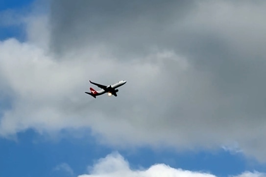 a qantas flight in mid-air with flames coming from one side
