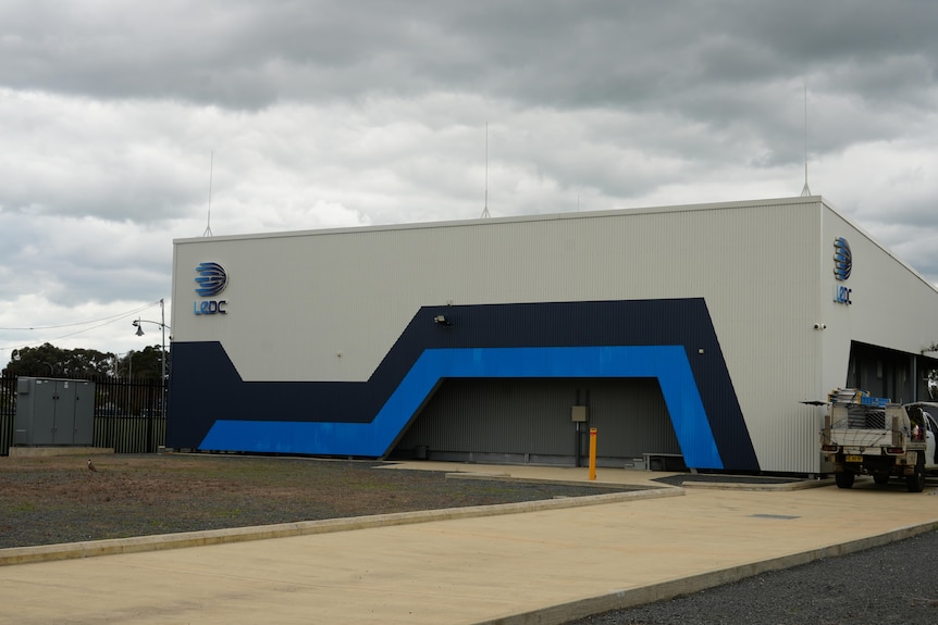 A large white, square industrial-looking building with an LeDC logo sits on a concrete expanse.