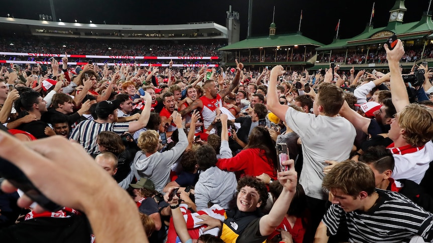 A large group of delighted Sydney Swans fans surround Lance Franklin on the SCG after his 1,000th AFL goal.