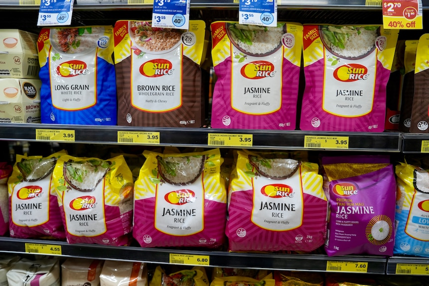 Shelves of colourful packets of SunRice rice lined up in a supermarket.