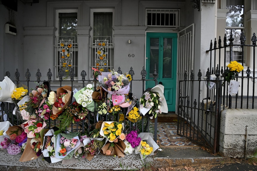 Bouquets of flowers are placed through the fence of a Paddington home in Sydney