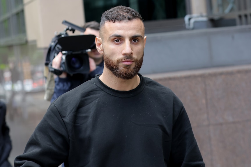 A man leaving a courthouse followed by a camera