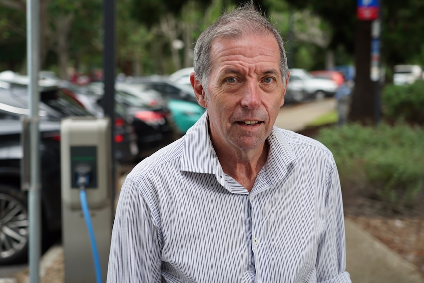 A man wearing a collared shirt and half smiling.