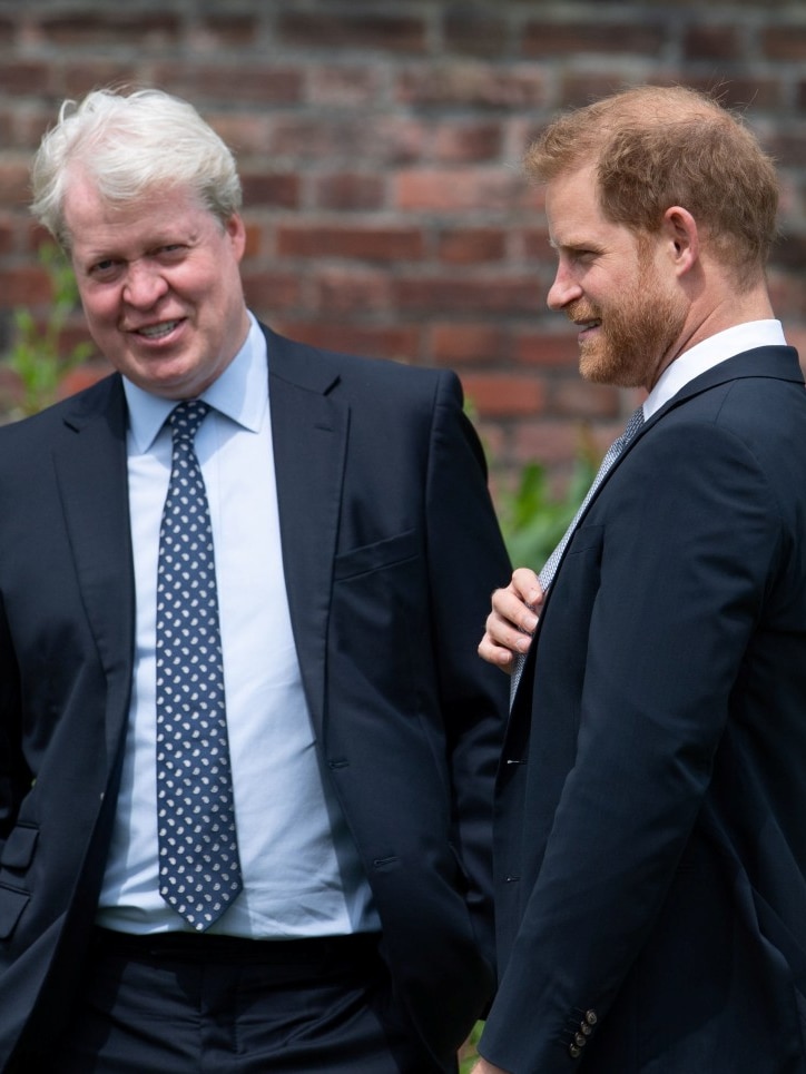 Two men in suits speaking outside and smiling.