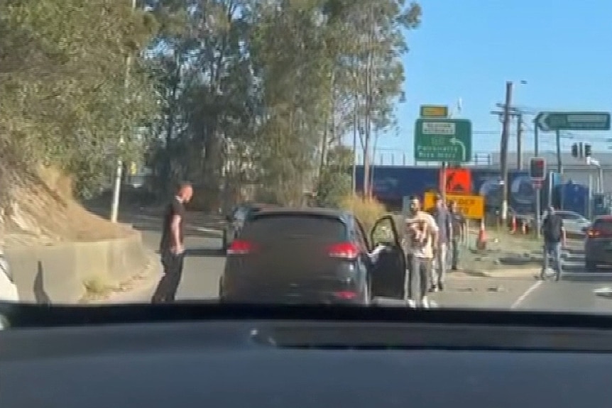 a number of people surround a car thatg was hijacked in sydney's west