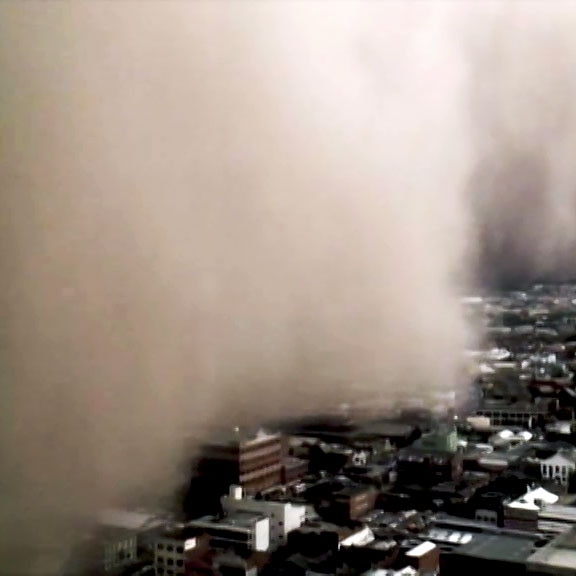 Birds-eye view of a massive dust cloud rolling over houses.