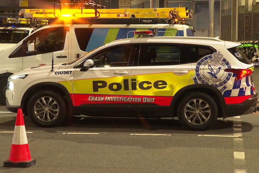 A police car with "crash investigation unit" on its side is parked in a car park.
