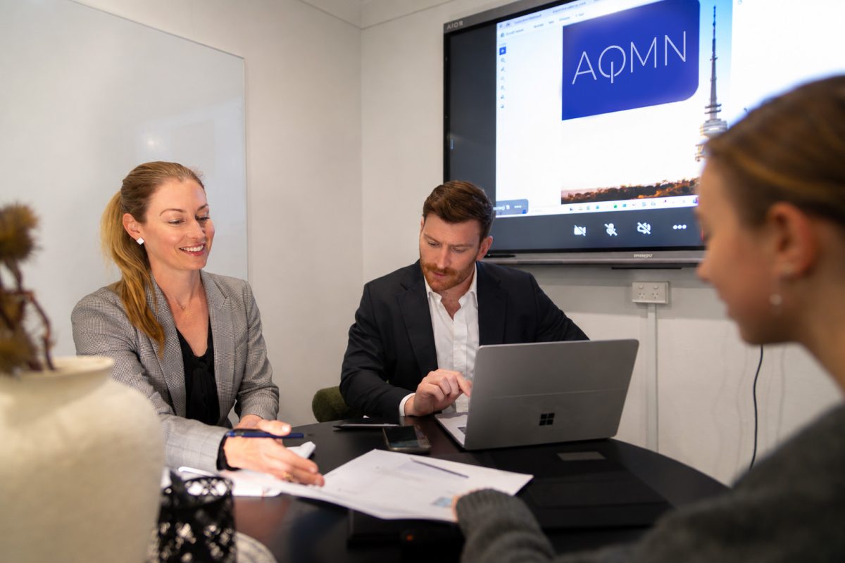 Emma Haskard and Matthew Bautz from AQMN Legal sitting at a table talking to a client
